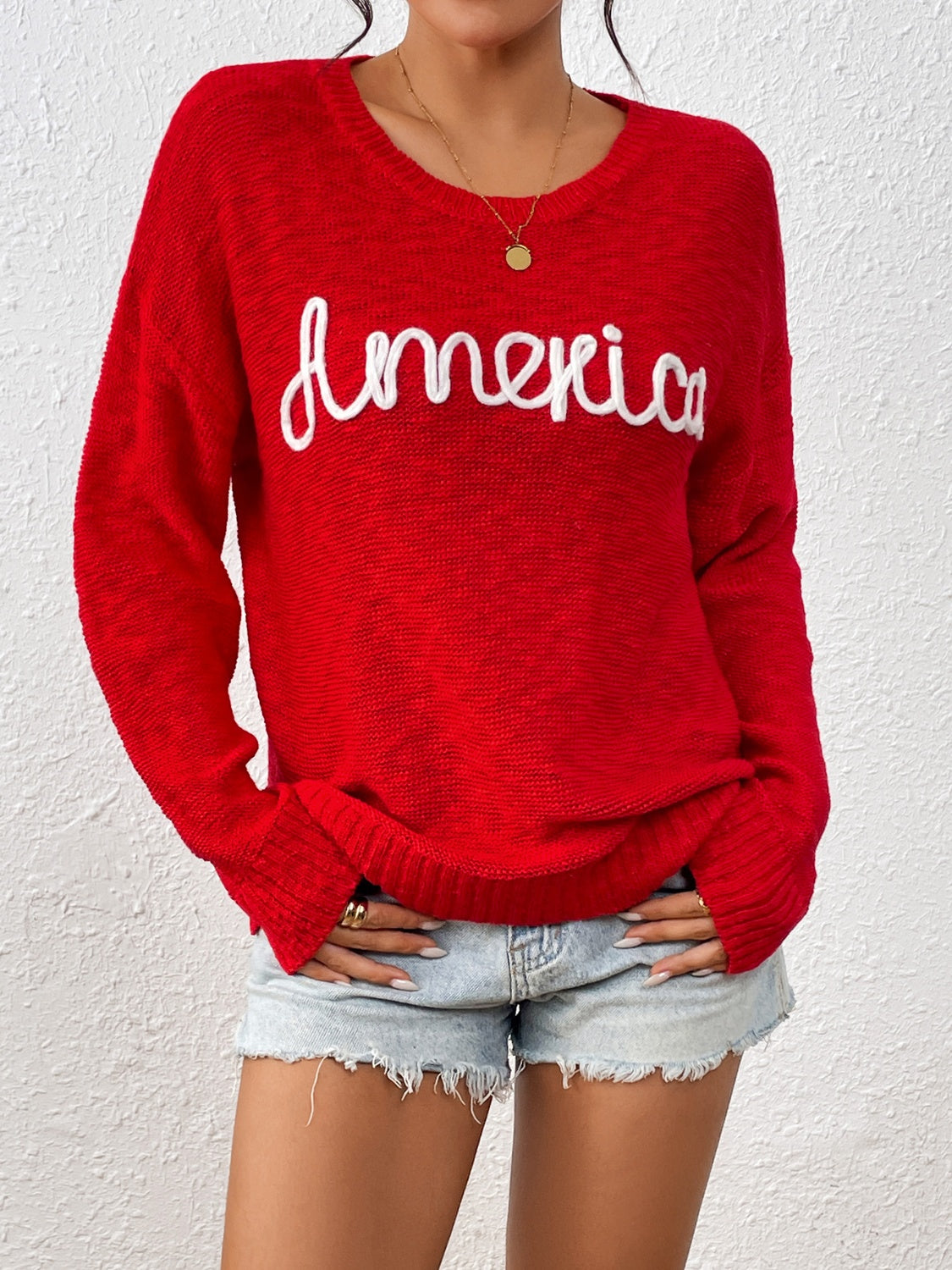 Red long sleeved sweater with the word America across the chest